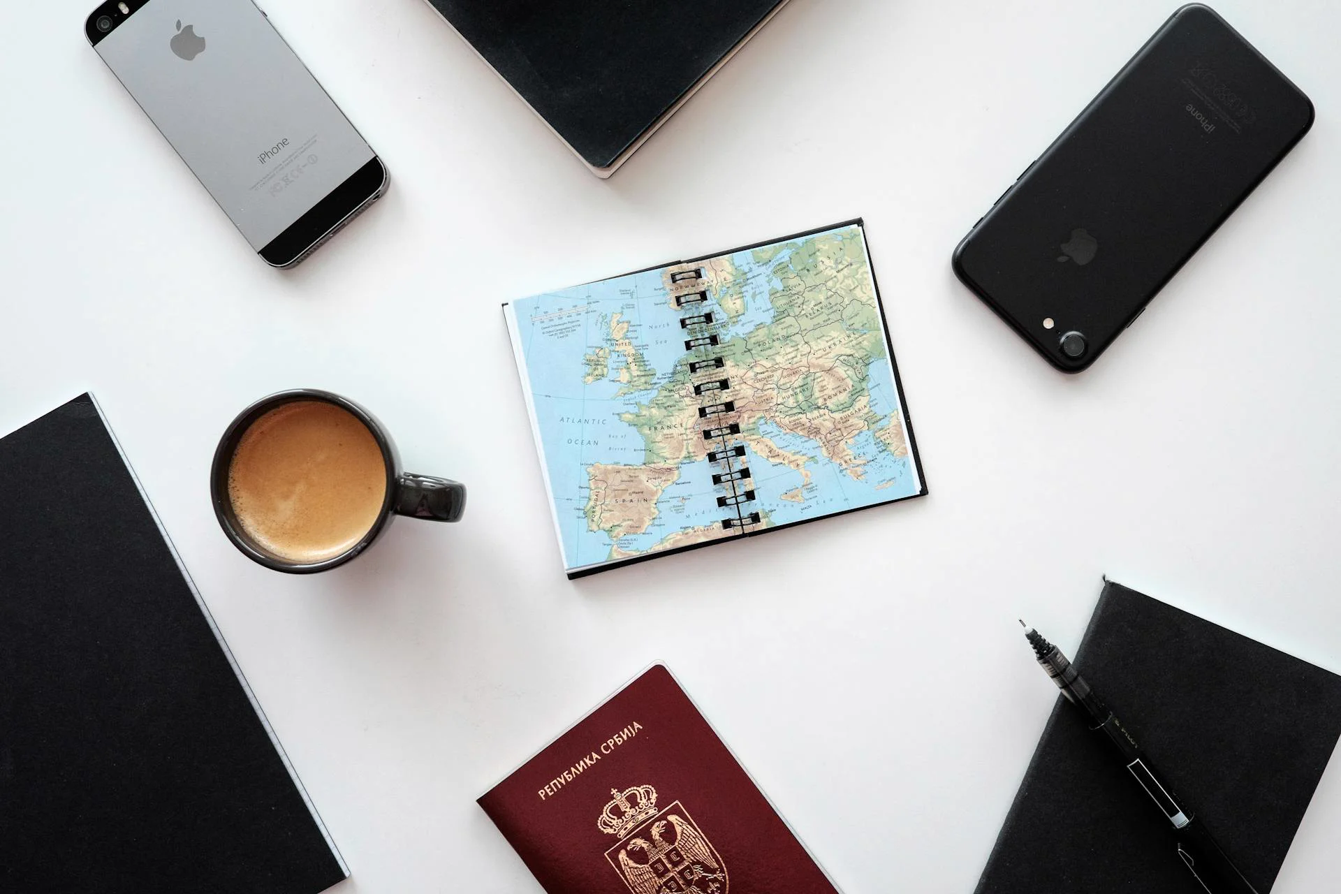 Flat lay of a Europe map, two phones, passport, and coffee — the Explorer is grounded in curated city data