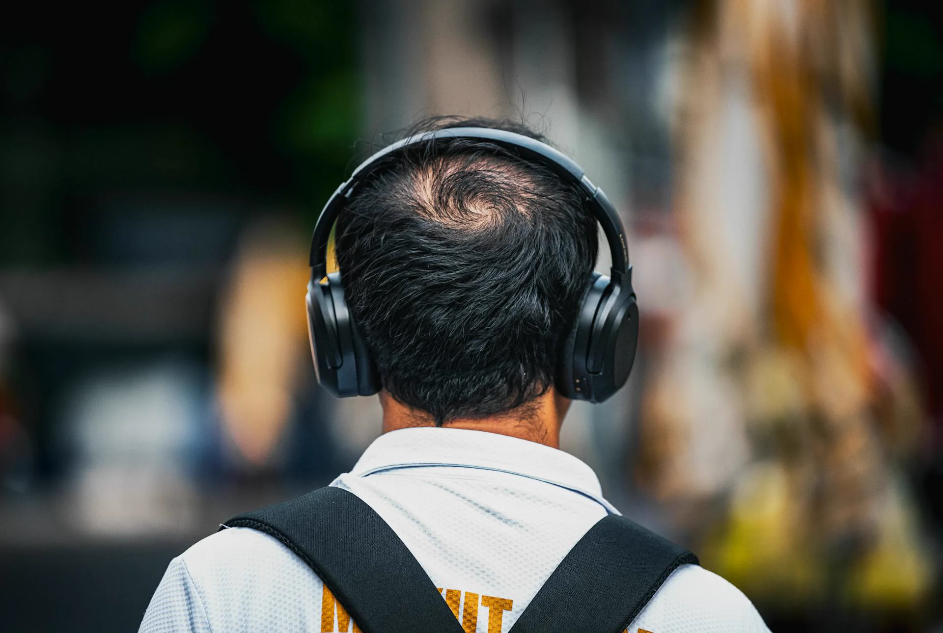 Traveler listening to an audio guide through over-ear headphones in a city street