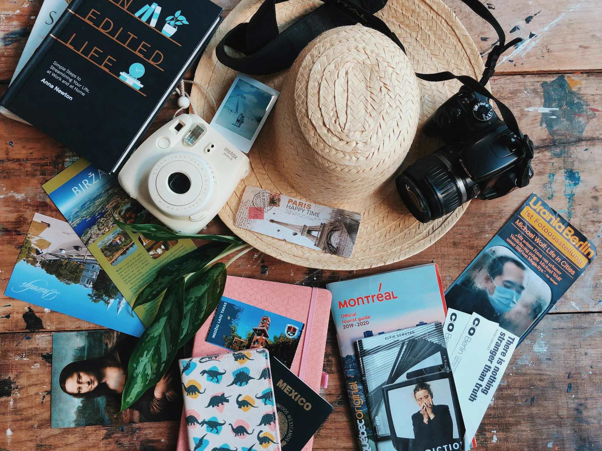 Flat lay of curated travel guidebooks, cameras, postcards and notebooks